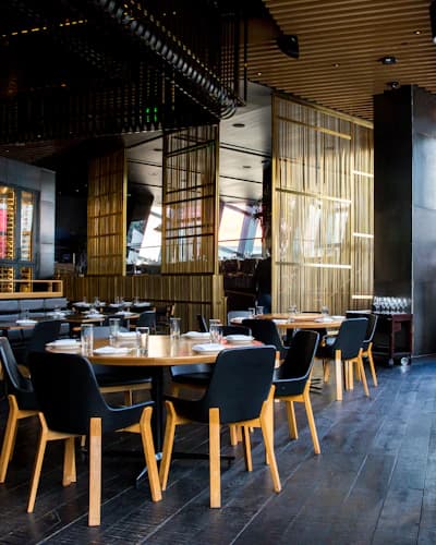 Salão de restaurante com mesas postas e iluminação baixa