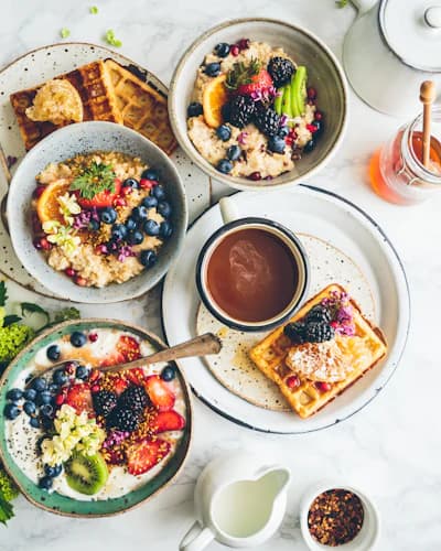 Mesa de café da manhã com tigelas de frutas e waffles