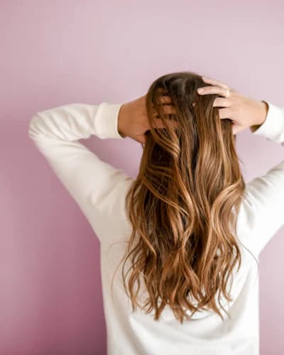Cabelo longo em destaque sobre parede rosa