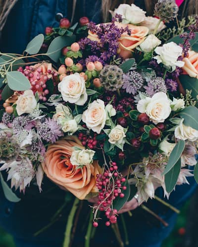 Buquê de flores variadas segurado com as duas mãos