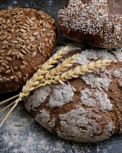 Pães artesanais e espigas de trigo sobre bancada enfarinhada